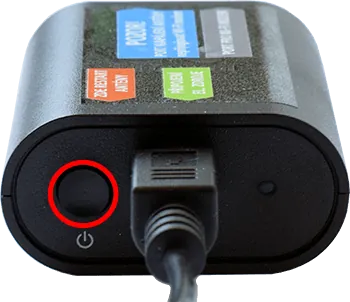 Detail napájecího adaptéru s tlačítkem zapnutí a připojeným napájecím kabelem